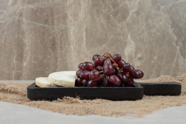 美味新鲜的红葡萄和白奶酪放在黑板上葡萄簇奶酪