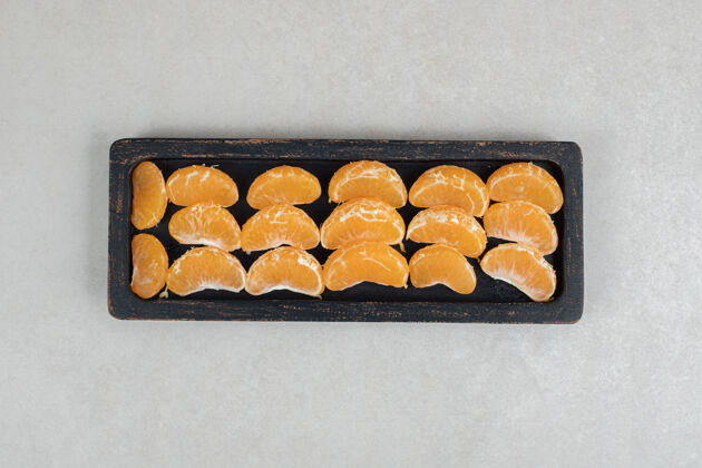 水果黑盘子上的橘子汁切片营养分割