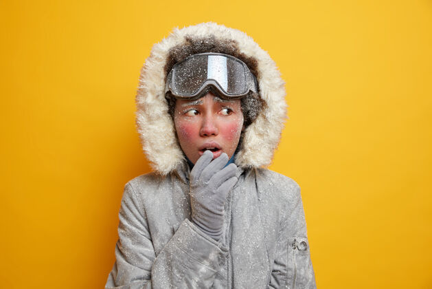 季节满脸是冰的困惑的少数民族妇女感到寒冷 把目光移开 戴上冬季夹克手套 在寒冷的天气里冻僵了霜冻紧张红色