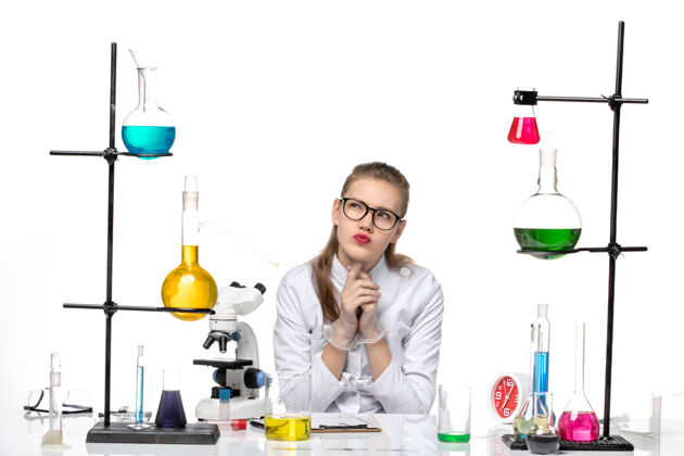 研究前视图穿着医疗服的女化学家坐在浅白背景上 化学大流行性冠状病毒前面医学专业
