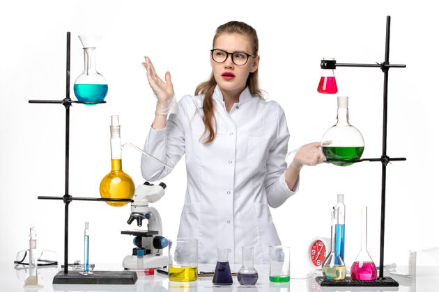 女化学家前视图穿着医疗服的女化学家在浅白色背景上用不同的溶液工作化学大流行性冠状病毒医生化学白