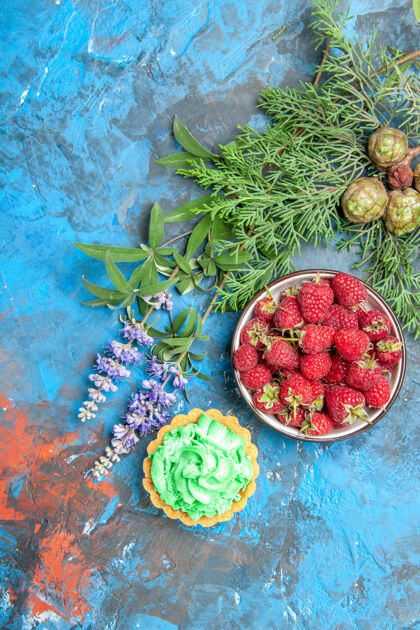 庆祝浆果碗的顶视图 蓝色表面上的小馅饼和树枝树枝农产品可食用水果