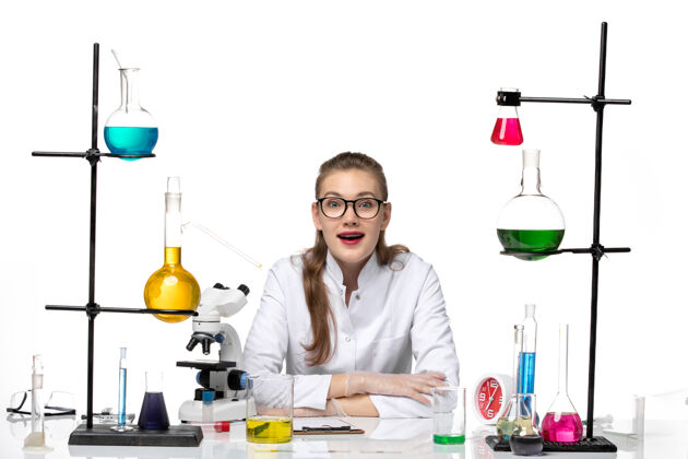 专业前视图穿着医疗服的女医生坐在白色背景上 解决方案化学大流行健康问题人实验化学