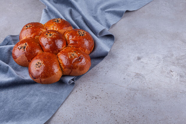 花芝麻香面包放在石头背景上卷面包房料理