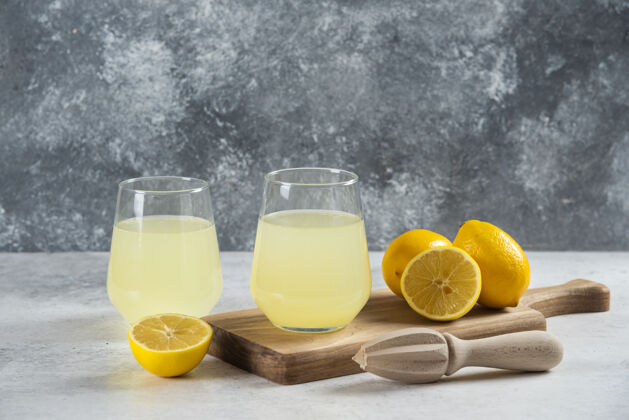 木头在木板上放两杯新鲜的柠檬水柠檬水杯子柑橘