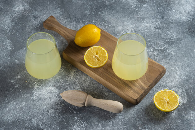 柑橘两杯新鲜柠檬汁和木铰刀桌子柠檬果汁