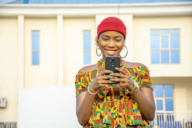 年轻美丽的非洲年轻女子微笑着在户外使用手机公园快乐电话