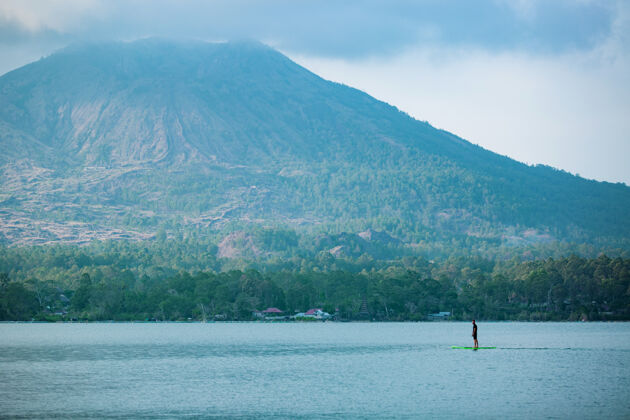 年轻一个男人在湖边骑冲浪板运动娱乐水