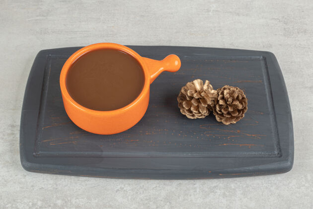 一杯咖啡和松果放在深色盘子里卡布西诺美味的咖啡