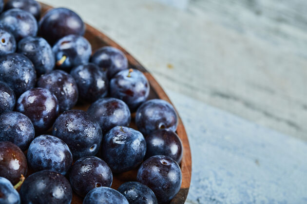 成熟花园李子在一个蓝色的背景板高品质的照片水果浆果石头