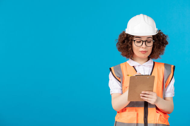 制服前视图穿着制服的女建筑工人在蓝色上写笔记女商人秘书笔记