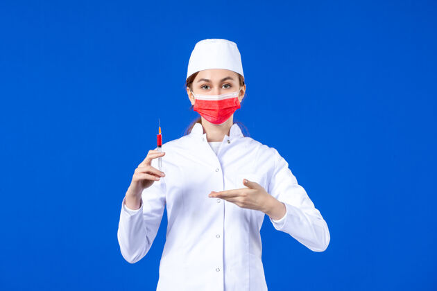 流行病正面图：身穿白色医疗服的女护士 戴着红色面罩 手上拿着蓝色针剂西装女护士注射