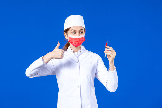病毒正面图：身穿白色医疗服的女护士 戴着红色面罩 手上拿着蓝色针剂医院面罩男人