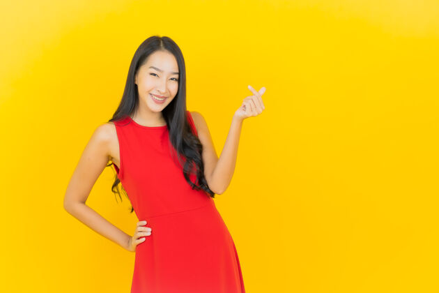 女人肖像美丽的亚洲年轻女子穿着红色连衣裙微笑着行动在黄色的墙上紫色亚洲人女人