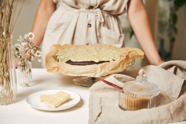 美食年轻的女面包师在白色的桌子上做着美味的奶油巧克力蛋糕美味奶油桌子