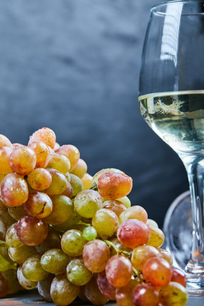 酒庄一束葡萄和一杯白葡萄酒在蓝色背景上高质量的照片自然酒杯串