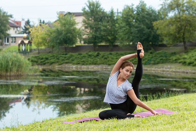 健身年轻漂亮的女人在绿色公园做瑜伽练习集中自然瑜伽