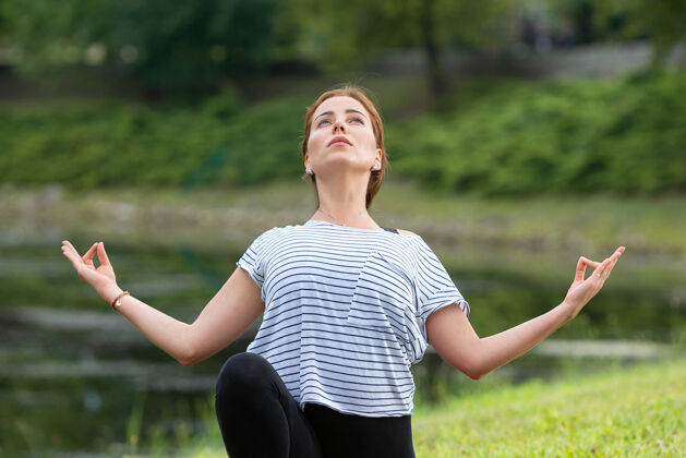 女人年轻漂亮的女人在绿色公园做瑜伽练习女性早晨瑜伽