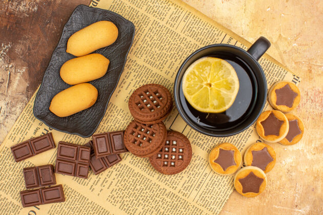 饮食不同的饼干和茶在混合颜色的桌子上的一个黑色杯子俯视图不同饼干混合健康