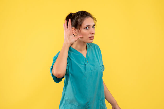 病毒前视图穿着医用衬衫的女医生在黄色背景上聆听女医生护士衬衫