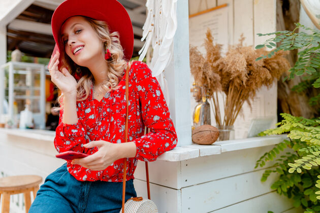 享受迷人的时尚金发微笑的女人在稻草红帽子和衬衫夏季时尚装咖啡馆使用手机帽子魅力外表