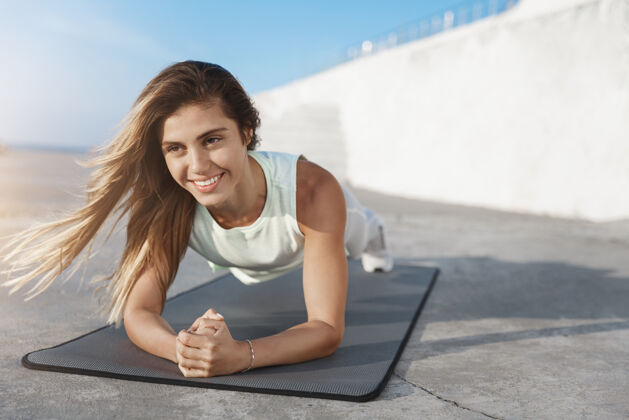 训练有动力有吸引力的健康高加索女运动员微笑在木板力量锻炼运动运动装体操