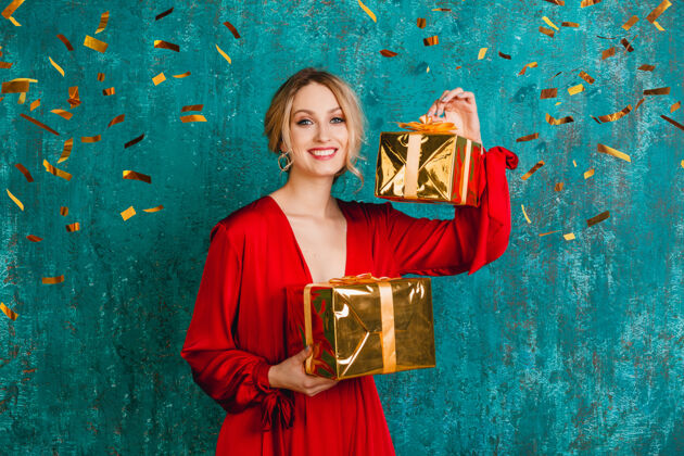 礼物迷人的快乐微笑的女人穿着时尚的红色连衣裙 用礼物庆祝圣诞节和新年礼物盒子乐趣
