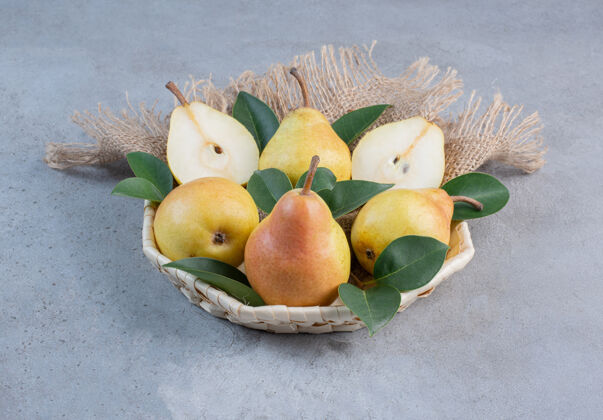 篮子美味的梨和装饰性的叶子放在大理石背景的小篮子里风味健康梨