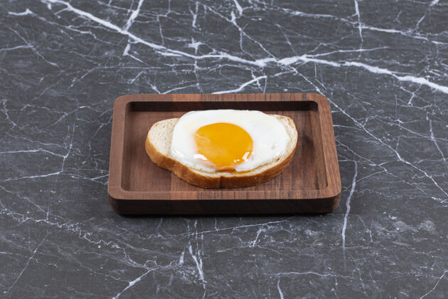 面包把煎鸡蛋放在面包上 切成薄片放在木板上 放在大理石表面可口风味煎蛋
