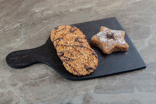 糕点脆皮饼干和星型饼干放在深色板上烘焙芝麻美食