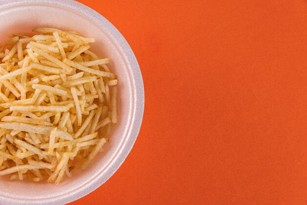 食物橙色背景上有土豆秸秆的白色碗特写乡村素食