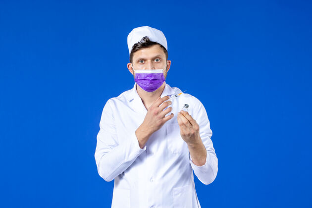 大流行男医生的前视图 穿着医疗服 戴着蓝色的疫苗注射面罩药品实验室外套套装