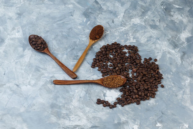 豆子咖啡豆配速溶咖啡 咖啡粉 咖啡豆放在木制勺子里 在浅蓝色大理石背景上特写食物大理石