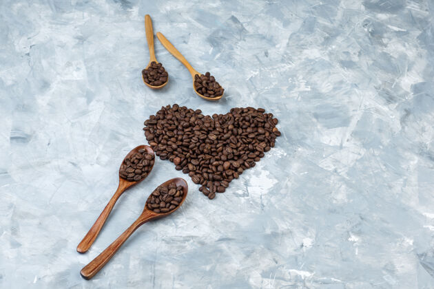 香味咖啡豆放在灰色灰泥背景上的木勺里高角度视图咖啡新鲜咖啡馆