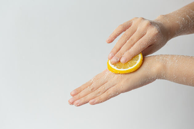 护理年轻女子用天然柠檬磨砂膏擦手上的白色表面清洁白色过程