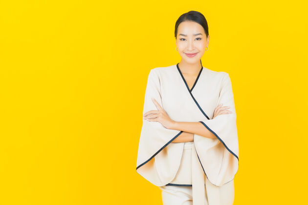 商业女性美丽的亚洲年轻商业女性在黄色墙上穿着白色西装微笑的画像人事业朋友