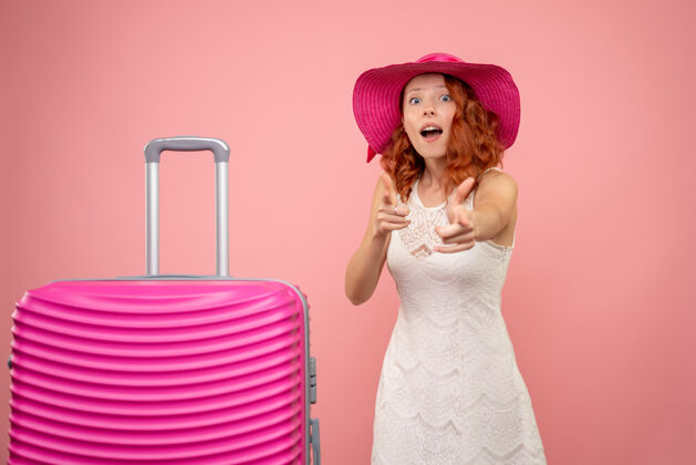 女士年轻的女性游客与粉红色的帽子和粉红色的墙壁上的包的正面视图夏天美丽可爱