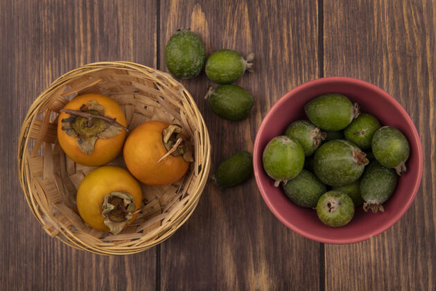 饮食在木制表面的桶上放着柿子水果的碗上的新鲜绿色的飞珠的俯视图食品美味新鲜