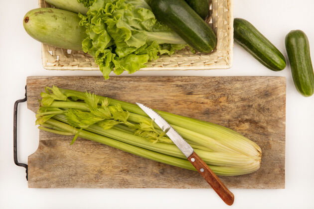 素食顶视图新鲜的芹菜在一个木制的菜板上与黄瓜西葫芦和生菜在一个白色的表面桶刀新鲜有机饮食