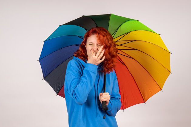 空气白色墙壁上带着彩色雨伞的年轻女性的正视图掩护前面情绪