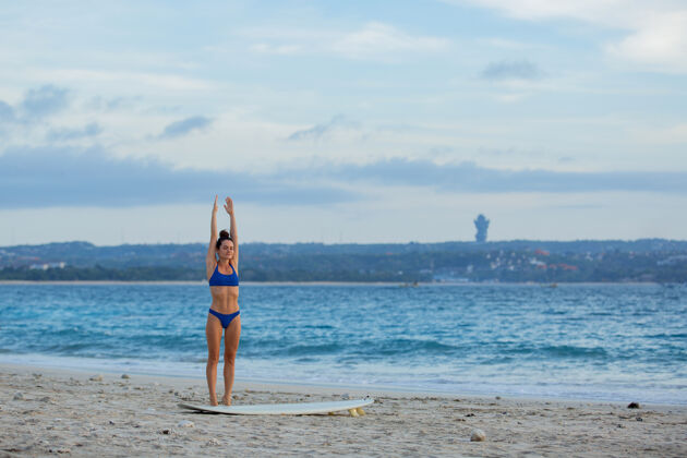 沙滩美丽的女孩伸展在沙滩上冲浪板冲浪成人沙滩