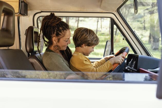 旅行侧视图：一个女人抱着儿子开车驾驶汽车家庭