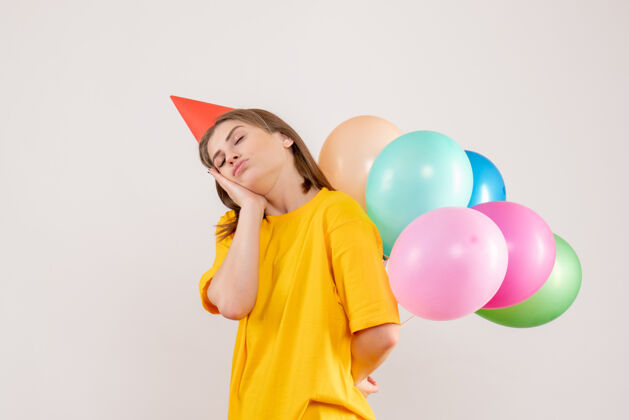 吹年轻的女性把彩色的气球藏在白色的背上看回来气球