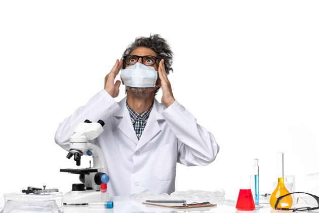化学正面图中年科学家穿着特制的西装 戴着面具围坐在桌子旁 拿着解决方案观点技术人员桌子