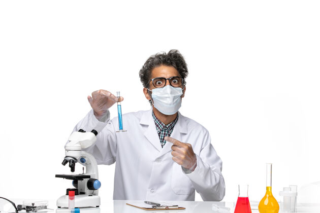 专业正面图中年科学家穿着特制的衣服坐着拿着装有溶液的烧瓶拿着实验室化学