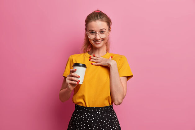 满意年轻漂亮的欧洲女孩积极地咯咯笑 为某事喝彩 喝外卖咖啡 满意地微笑 在快乐的公司里玩得开心外卖咖啡欧洲