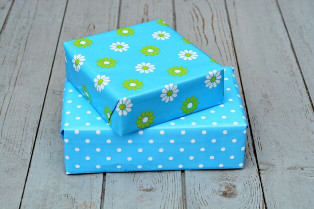 圣诞节特写镜头的两个礼品盒在蓝色包装堆叠在一个木制表面上的对方顶部礼物波尔卡地板