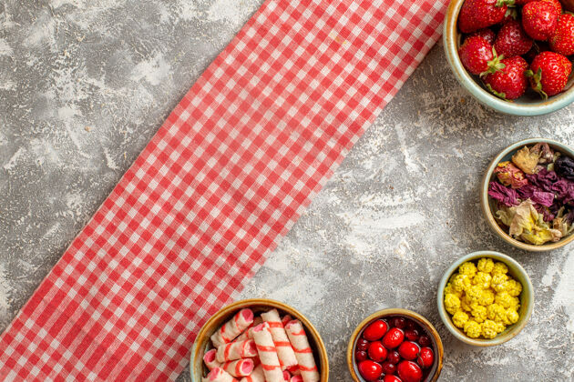 糖果顶视图新鲜的红色草莓和糖果的白色表面浆果新鲜糖果水果袋子食物新鲜的红草莓