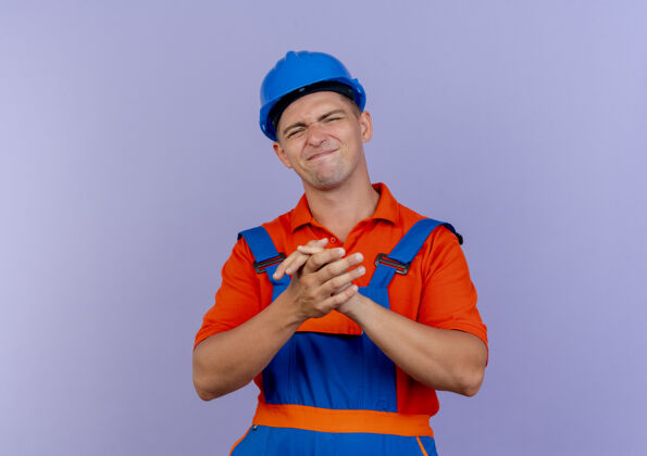 建筑工人身着制服 头戴安全帽的年轻男性建筑工人高兴地在紫色地板上展示握手手势安全握手年轻
