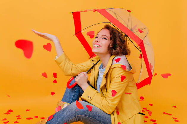 雨感兴趣的棕色头发的女孩享受心雨微笑迷人的女人穿着黄色外套坐在地板上用阳伞天气成人季节